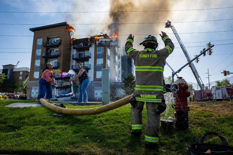 A member of the Sandy City Fire Department motions after connecting a hose to a fire hydrant as fellow firefighters respond to an apartment fire at 942 E. North Union Ave. near Hillcrest High School in Midvale on Friday, July 31, 2026.